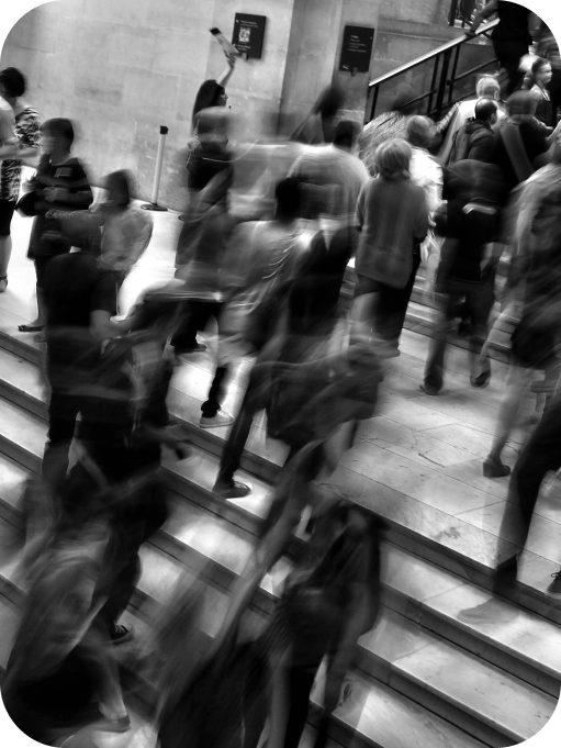 Blurred crowd of people walking up and down stairs in a busy public transit or urban indoor setting